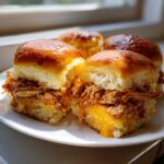 Close-up of two halves of amazing bbq chicken sliders filled with shredded meat and melted cheddar cheese.